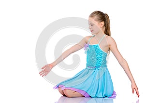 The little gymnast perform an acrobatic element on the floor.