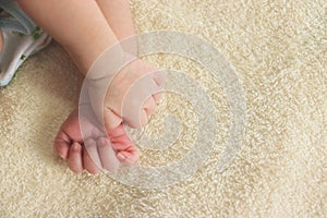 Little hands of newborn tiny Asian baby on a yellow blanket