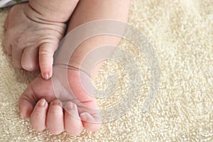 Little hands of newborn tiny Asian baby on a yellow blanket