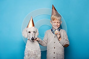 Little handsome boy with dog celebrate birthday. Friendship. Love. Cake with candle. Studio portrait over blue background