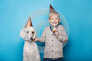 Little handsome boy with dog celebrate birthday. Friendship. Love. Cake with candle. Studio portrait over blue background