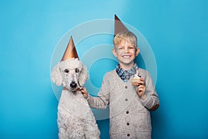 Little handsome boy with dog celebrate birthday. Friendship. Love. Cake with candle. Studio portrait over blue background