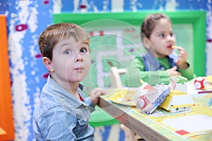 Little handsome boy and girl sit at table and eat