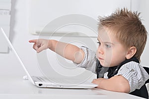 Little handsome boy sits with a computer