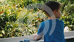 Little happy 4-6 year old boy in safari tour boat sailing along beautiful exotic jungle river with sunny lush greenery.