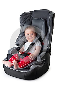 Little happy baby boy seats in a car seat studio isolated