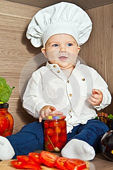 Little happy boy kid play in chef at kitchen and cook food