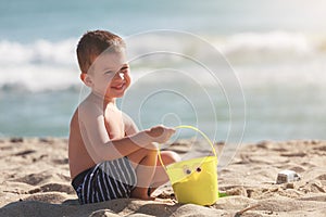 Little happy boy play with sand and toys on summer beach