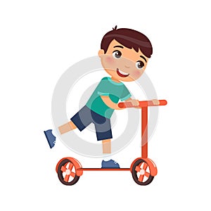 Little happy boy rides a scooter. The child rides with a kick.