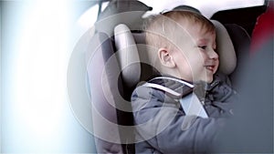 Little happy boy is sitting in the car seat and smiling.