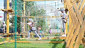 A little happy Caucasian girl is a child in an adventure park in protective gear on a summer day. Rope park. nature