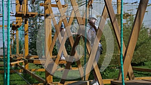 A little happy Caucasian girl is a child in an adventure park in protective gear on a summer day. Rope park. nature