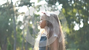 Little happy child girl chasing soap bubbles outdoors in summer.