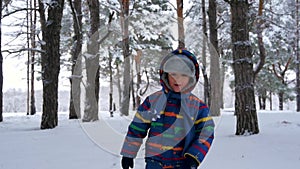 A little happy child runs to meet the camera among the snow-covered trees in the winter. The concept of family, outdoor