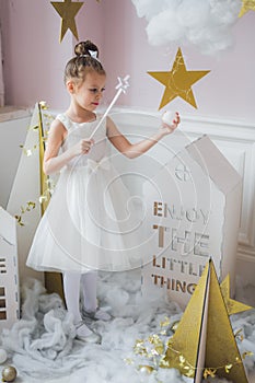 Little happy fairy or angel with magic wand on Holiday theme. Portrait of pretty caucasian little angel wearing white