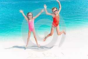 Little happy funny girls have a lot of fun at tropical beach playing together.