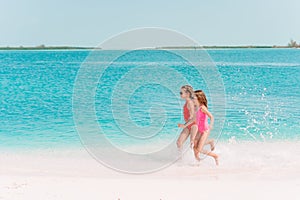 Little happy funny girls have a lot of fun at tropical beach playing together.