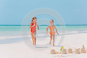 Little happy funny girls have a lot of fun at tropical beach playing together.