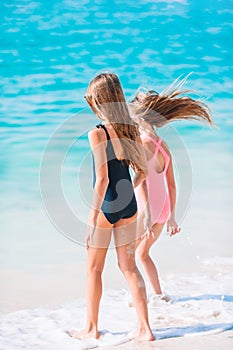 Little happy funny girls have a lot of fun at tropical beach playing together