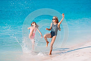 Little happy funny girls have a lot of fun at tropical beach playing together