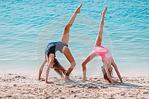 Little happy funny girls have a lot of fun at tropical beach playing together.