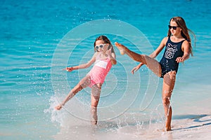 Little happy funny girls have a lot of fun at tropical beach playing together.