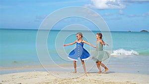 Little happy funny girls have a lot of fun at tropical beach playing together. SLOW MOTION