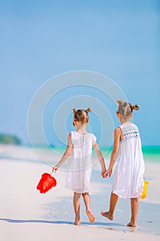 Little happy funny girls have a lot of fun at tropical beach playing together. Sunny day with rain in the sea