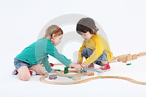 Little happy girl and boy arrange trees near wooden railway