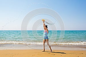 Little happy girl in bright swimsuits throwing the water around itself on the beach. Family vacation