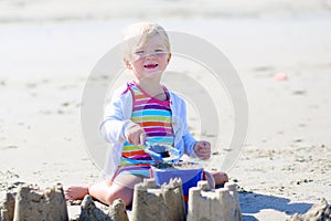 Little happy girl building sand castles on the beach