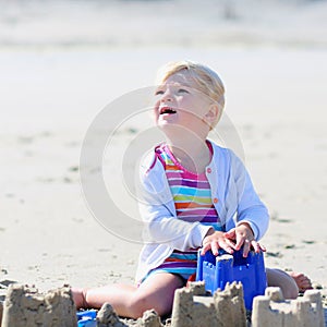 Little happy girl building sand castles on the beach