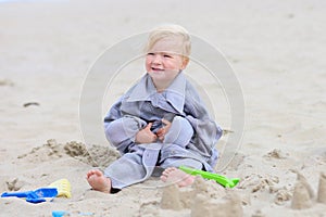 Little happy girl building sand castles on the beach