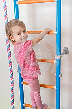 Little happy girl climbing the ladder