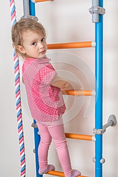 Little happy girl climbing the ladder