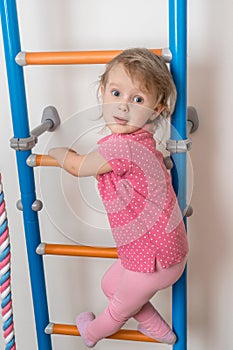 Little happy girl climbing the ladder