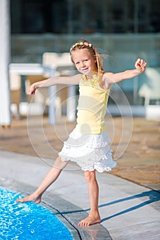 Little happy girl enjoy vacation near outdoor swimming pool