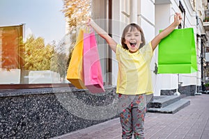 Little happy girl is holding colorful shopping bags