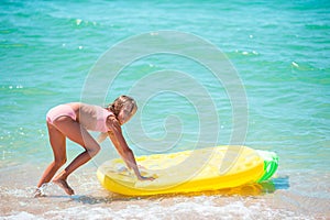 Little happy girl with inflatable air mattress in the sea having fun