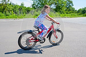 A little happy girl learns to ride a bike in the park photo