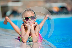 Little happy girl in outdoor swimming pool enjoy her vacation