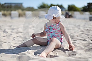 Little happy girl playing on white sand beach