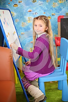 Little happy girl plays with magnets in children room. photo