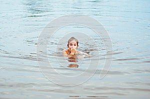 Little happy girl plays with water and splashes of water in the sea