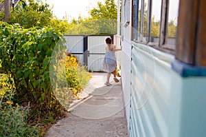 little happy girl running around the corner of a house in a summer village