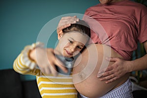 Little happy girl takes a picture of herself and her mother`s belly