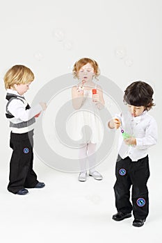 Little happy girl and two boys blow bubbles on