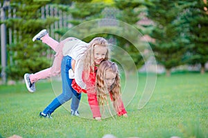 Little happy girls are having fun around on a green lawn