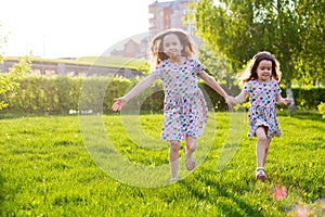 Little happy girls on a walk on a summer evening at sunset in the park. Sisters
