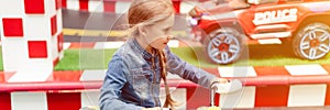 Little happy kid girl fun riding an small electric cars on sport ground in a playground for entertainments. children riding in the